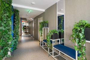 a hallway with plants on the walls and blue benches at Riva Mamaia Beach Apart Hotel in Mamaia