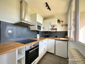 une cuisine avec des placards blancs et un comptoir en bois dans l'établissement Le Golden View - Vue Imprenable & Parking Gratuit, à Chambéry