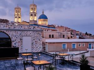 patio na dachu ze stołami i krzesłami oraz dwoma wieżami w obiekcie Argini Syros w mieście Ermupoli
