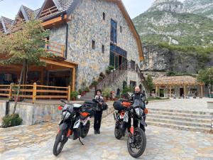 dos personas en motocicleta estacionadas frente a un edificio en RIREYANA, en Tamarë