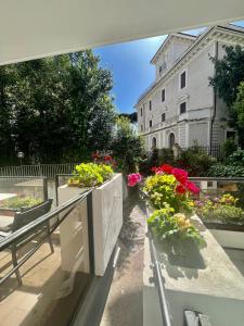 a balcony with flowers and a building in the background at Villa Borghese Green Apartment in Rome