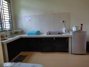 La cuisine est équipée d'un comptoir, d'un évier et d'un réfrigérateur. dans l'établissement Homestay Al amin 2, à Kampong Sura Tengah