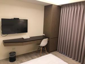 um quarto com uma secretária, uma televisão e uma cadeira em Sway Hotel - Fenjia em Taichung