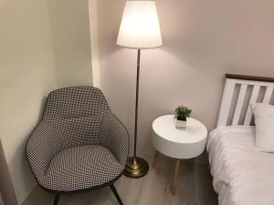 a bedroom with a chair and a lamp next to a bed at Sway Hotel - Fenjia in Taichung