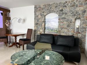 a living room with a black couch and a stone wall at Souterrain Ferienwohnung in Haigerloch