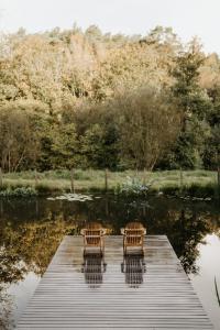 dos sillas sentadas en un muelle junto a un lago en Gîtes du Bulz, en pleine forêt proche de la mer, en Pleyber-Christ