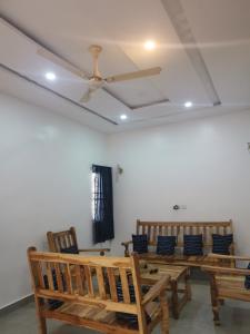 una sala da pranzo con panche in legno e ventilatore a soffitto di Le Havre Béninois a Cotonou