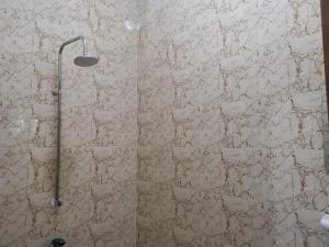 y baño con ducha y pared de piedra. en Le Havre Béninois en Cotonú