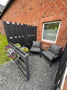 eine Terrasse mit 2 Stühlen und Blumen neben einem Backsteingebäude in der Unterkunft Große Ferienwohnung in Ostseenähe in Schönberg