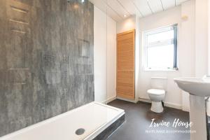 a bathroom with a tub and a toilet and a sink at Irvine Contractor Accommodation in Leigh