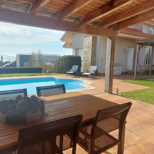 eine Terrasse mit einem Holztisch und einem Pool in der Unterkunft Casa con piscina, vistas y cerca de las playas in Vigo