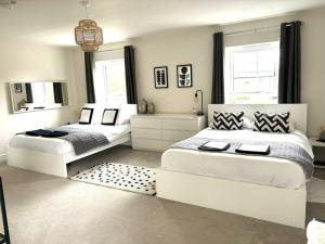 two beds in a white bedroom with a mirror at Stansted Coach House - Apartment Hotel in Elsenham