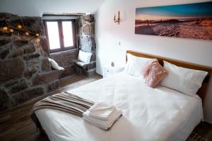 a bedroom with a bed with white sheets and pillows at Refúgio Nariz do Mundo (Casa do Meio) in Cabeceiras de Basto