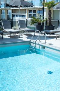 a swimming pool with chairs and an umbrella on a building at Hotel Europa in Lido di Jesolo