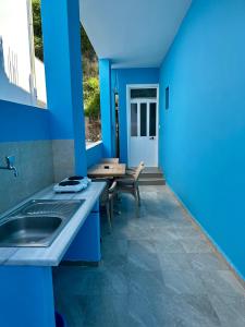 a blue kitchen with a sink and a table at Villa Denny in Borsh