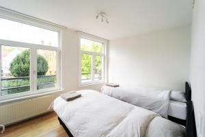 two beds in a room with two windows at Charmante rijwoning in Bruges