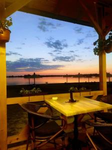 a table and chairs on a porch with a view of the water at Dream Lake in Palić