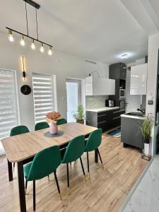 a kitchen and dining room with a wooden table and green chairs at B-Home in Göd