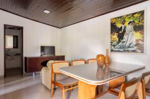 uma sala de jantar com uma mesa e cadeiras e um quadro em Pousada Demuner's House - Espaço Aconchegante Itaipava em Petrópolis