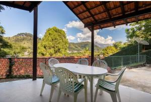 uma mesa branca e cadeiras num pátio com vista em Pousada Demuner's House - Espaço Aconchegante Itaipava em Petrópolis