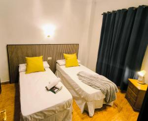 two beds with yellow pillows in a room at El Chivero in Fuengirola