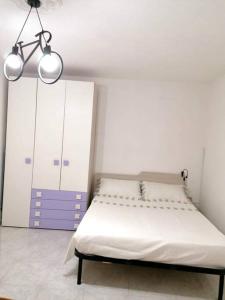 ein weißes Schlafzimmer mit einem Bett und zwei Kleiderschränken in der Unterkunft Monolocale Romeo in Locri