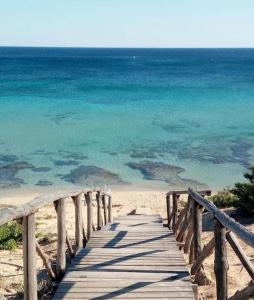 - un pont en bois sur une plage avec l'océan dans l'établissement Kalù-villetta nel Salento, à Maruggio