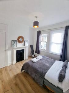 een witte slaapkamer met een bed en een open haard bij 2 bedroom-2 mins walk to Station in Kent
