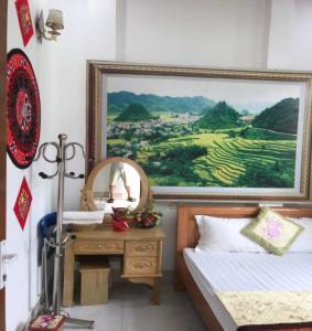 um quarto com uma pintura por cima de uma cama e uma secretária em Yen Minh Thien An Motel em Yên Minh