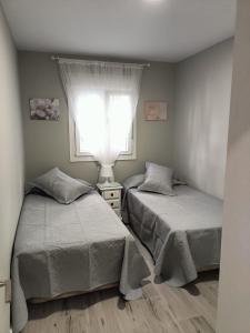 2 bedden in een slaapkamer met een raam bij Nuevo Garcia Lorca in Cádiz
