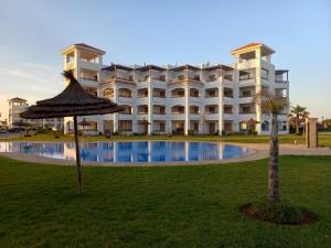 a large white building with a palm tree in front of it at Beralmar in Asilah