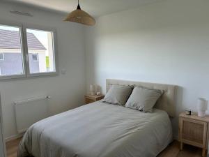 ein weißes Schlafzimmer mit einem großen Bett und einem Fenster in der Unterkunft Gîte des couleurs avec SPA in Chicheboville