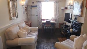 ein Wohnzimmer mit 2 weißen Sofas und einem Tisch in der Unterkunft Tanners Cottage in Cockermouth