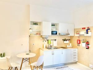 a kitchen with white cabinets and a table and chairs at Alcântara Studio 15 in Lisbon