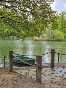 a green boat tied to a dock in a lake at Fresh and Sparkling - Free Parking in Crystal Palace