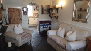 ein Wohnzimmer mit 2 Sofas und einer Uhr in der Unterkunft Tanners Cottage in Cockermouth