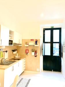 una cocina con armarios blancos y una puerta negra en Alcântara Studio 15, en Lisboa