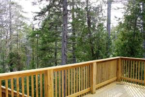 una terraza de madera con vistas al bosque en Log Cabin on Saltwater Cove, en Ellsworth