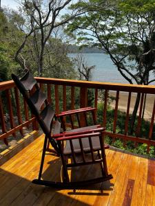 mecedora sentada en una terraza con vistas al agua en Playa Carao en Paquera