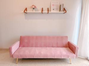 a pink couch in a living room with a shelf at Gold Coast Apartment PIK Lovely Stay Near Airport in Jakarta