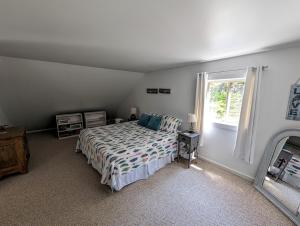 Schlafzimmer mit einem Bett und einem Fenster in der Unterkunft Sunset Cove Cottage private beach in Prospect Harbor