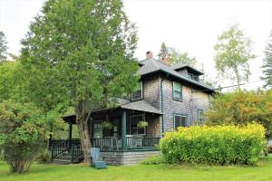 une maison ancienne avec une véranda et un arbre dans l'établissement Ocean Breezes Fire Pit, à Ellsworth