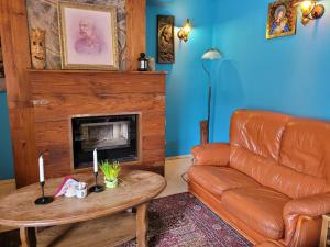 - un salon avec un canapé en cuir et une cheminée dans l'établissement Oberża Pod Kudłatym Aniołem, à Cisna