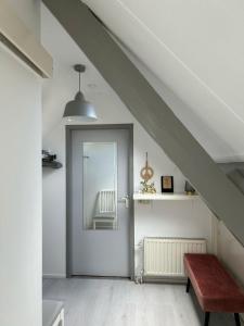 um quarto no sótão com uma porta que leva a uma cadeira em Guesthouse Katwijk aan Zee em Katwijk aan Zee