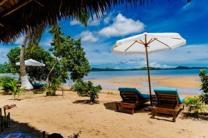 two chairs and an umbrella on a beach at Long Beach Resort, Nosy Be in Nosy Be