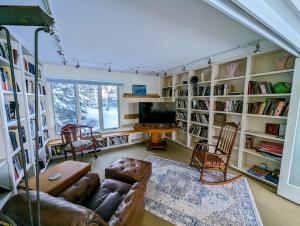 a living room with a couch and a tv and book shelves at Oceanfront Crackling Cove Cottage NEW in Prospect Harbor
