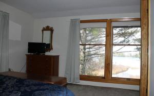 a bedroom with a large window and a television at Somes Pond Island Cottage in Southwest Harbor