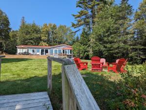 Prospect Harbor的住宿－Lone Pine Oceanfront Cottage，一群红色椅子在院子里,有房子