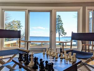 un tablero de ajedrez sobre una mesa en una habitación con ventanas en Lone Pine Oceanfront Cottage, en Prospect Harbor