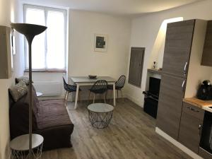 a living room with a couch and a table with chairs at Appartement climatisé Barjac centre ville in Barjac +2 photos